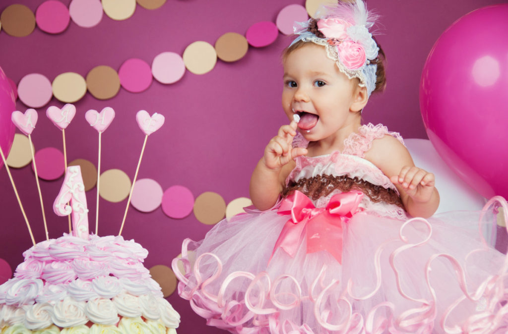 Portrait of a little cheerful birthday girl with the first cake. Eating the first cake. Smash cake.